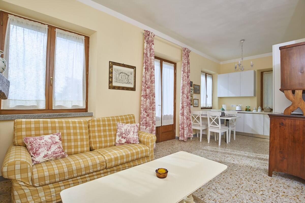 A living room with a checkered sofa, a coffee table, and a dining area with a white table and chairs.