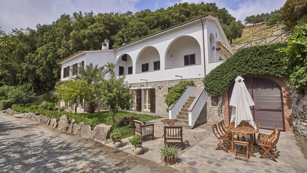 A white villa with a stone staircase, outdoor seating, and a lush garden. - Marciana Hills Apartments (Marciana)