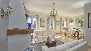 A spacious living area with a sofa, a dining table with chairs, and a chandelier. - Marciana Hills Apartments (Marciana)