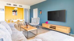 En moderne stue med sofa, sofabord, fjernsyn og spiseområde med stole og bord.