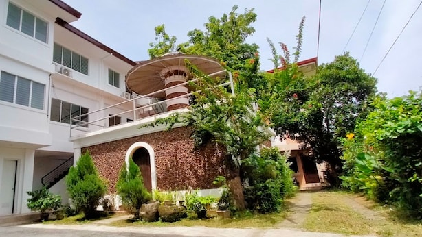 A two-story building with a balcony, a staircase, and a garden area with various plants. - OYO 799 Ddd Habitat Iloilo (Iloilo)