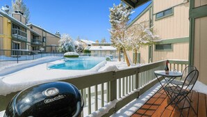 Un espace piscine avec un jacuzzi, entouré d’arbres et de bâtiments recouverts de neige.