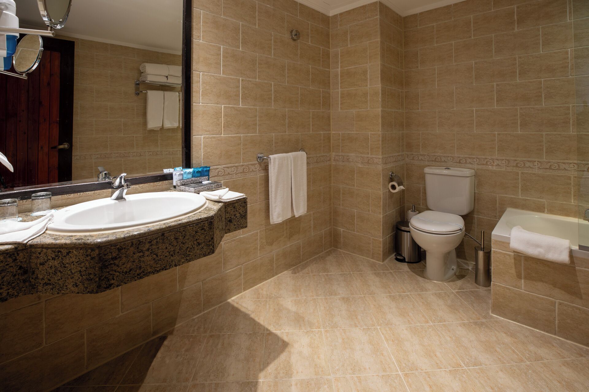 A bathroom with a granite countertop sink, a toilet, and a bathtub.