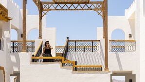 A white building with a wooden pergola and a staircase.