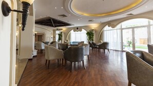 A spacious lobby with a high ceiling, elegant chandeliers, and a view of the outdoors through large windows.