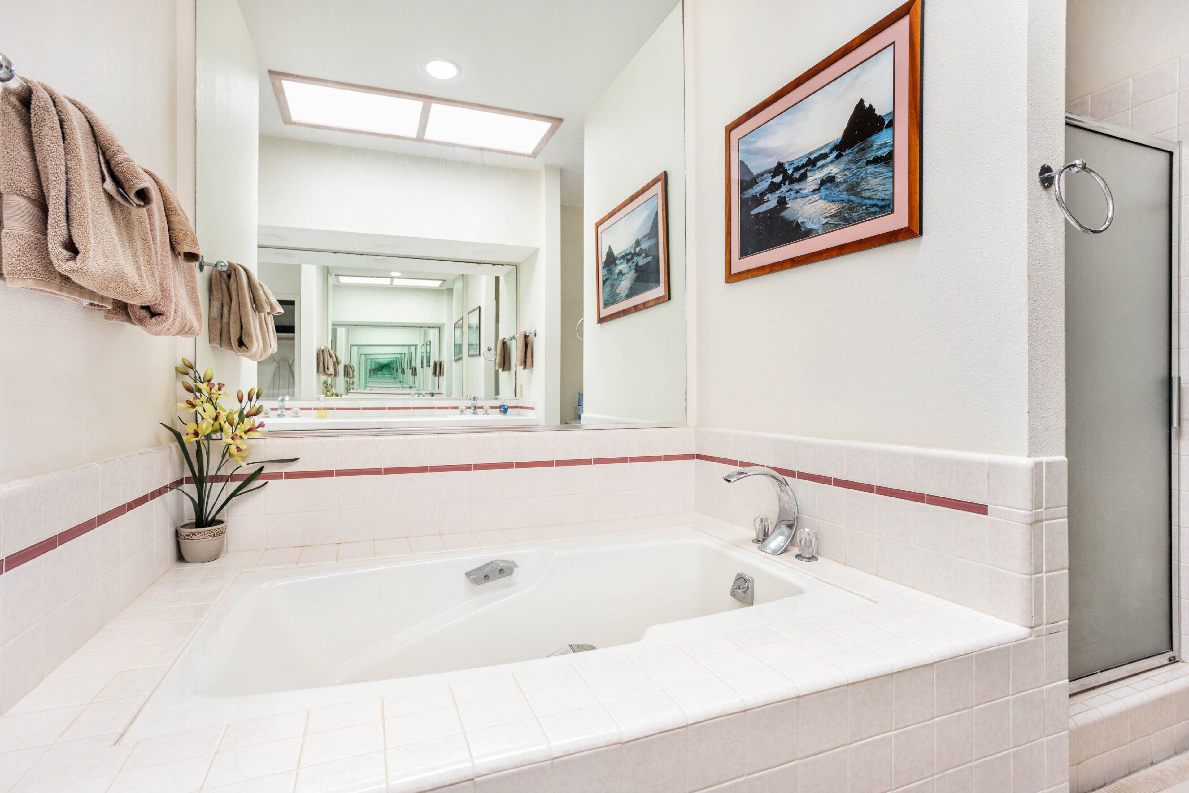 A modern bathroom with a large bathtub, a shower, and a mirror.