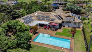 Une propriété résidentielle dotée d’une piscine, de panneaux solaires et d’un patio couvert.