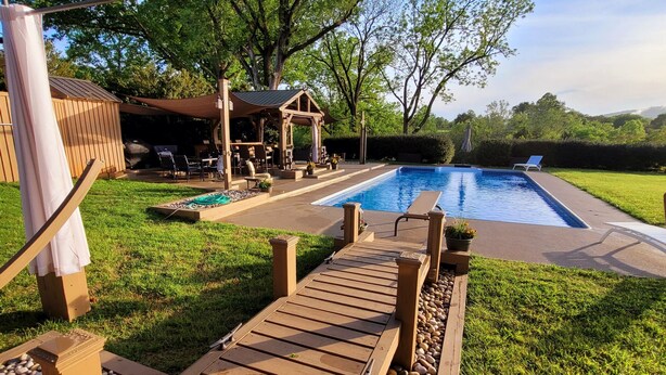 A wooden deck leading to a swimming pool with a pergola and outdoor seating area. - Cottage on quiet farm close to town and wineries  (Charlottesville)