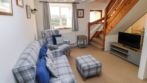 A cozy living room with a sofa set, a television, and a staircase leading to an upper level.