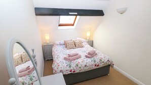 A bedroom with a bed, bedside tables, a mirror, and a skylight.