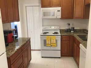Kitchen equipped with a stove, microwave, sink, and granite countertop.