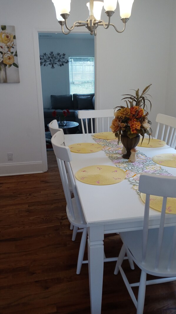 Guests can dine in style with a table set for six, surrounded by comfortable chairs and a beautiful floral arrangement.