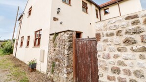 A two-story building with a stone wall and a wooden gate.