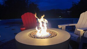 A round outdoor fire pit with flames, surrounded by Adirondack chairs. - Bourbon Country Lodge • 5 Acre Resort Pool+Hot Tub (Louisville)