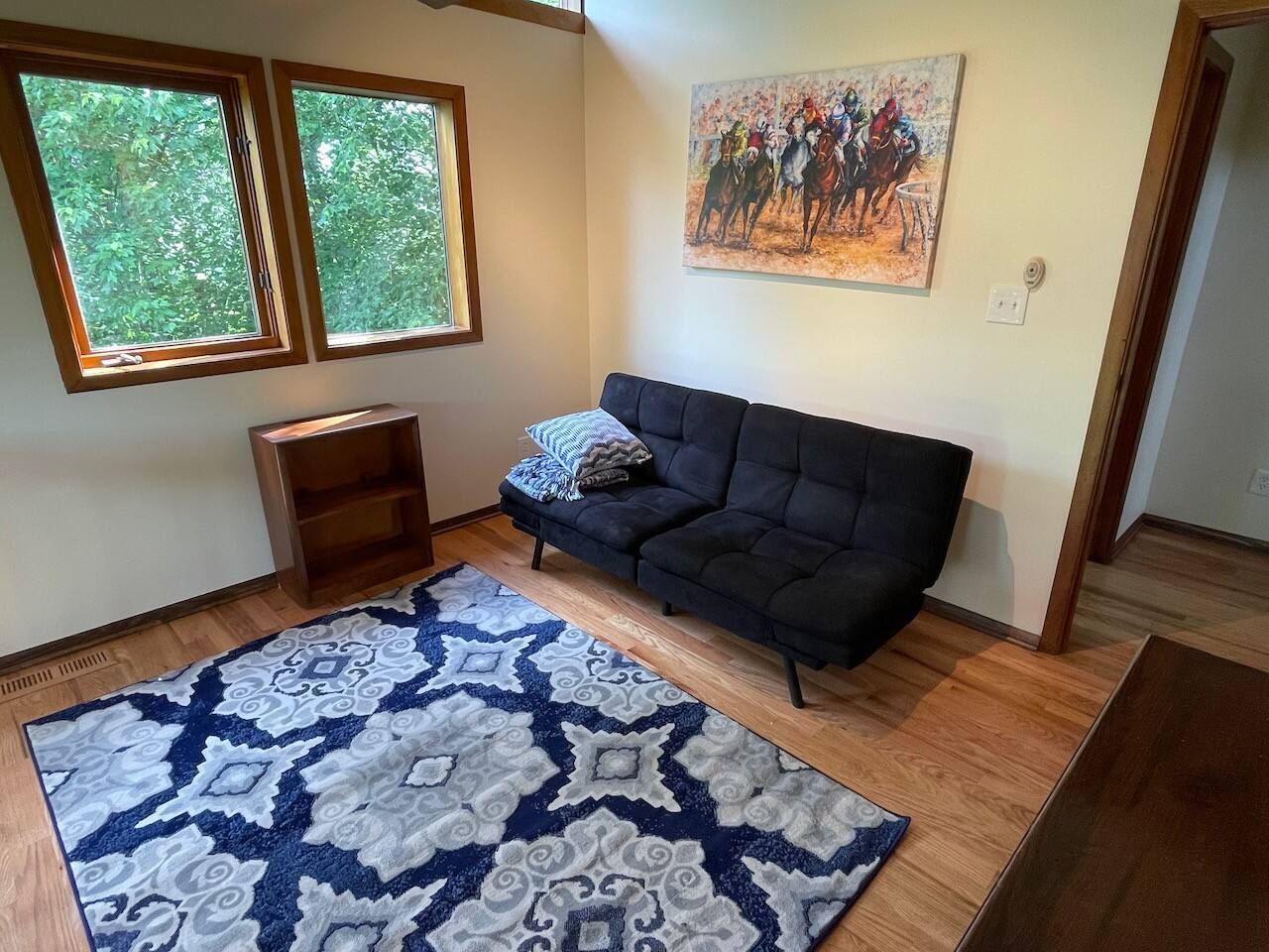 Ein Wohnzimmer mit einer dunklen Couch, einem gemusterten Teppich und einem Bild an der Wand.