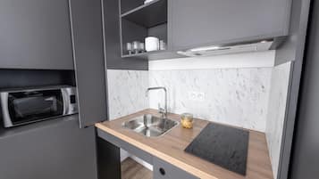 Une cuisine moderne équipée d’un four à micro-ondes encastré, d’un évier et d’un plan de travail.