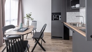 A modern kitchen with a wooden table and black chairs, a built-in microwave, and a marble backsplash. - Appart'City Collection Saint Germain en Laye (Saint-Germain-en-Laye)