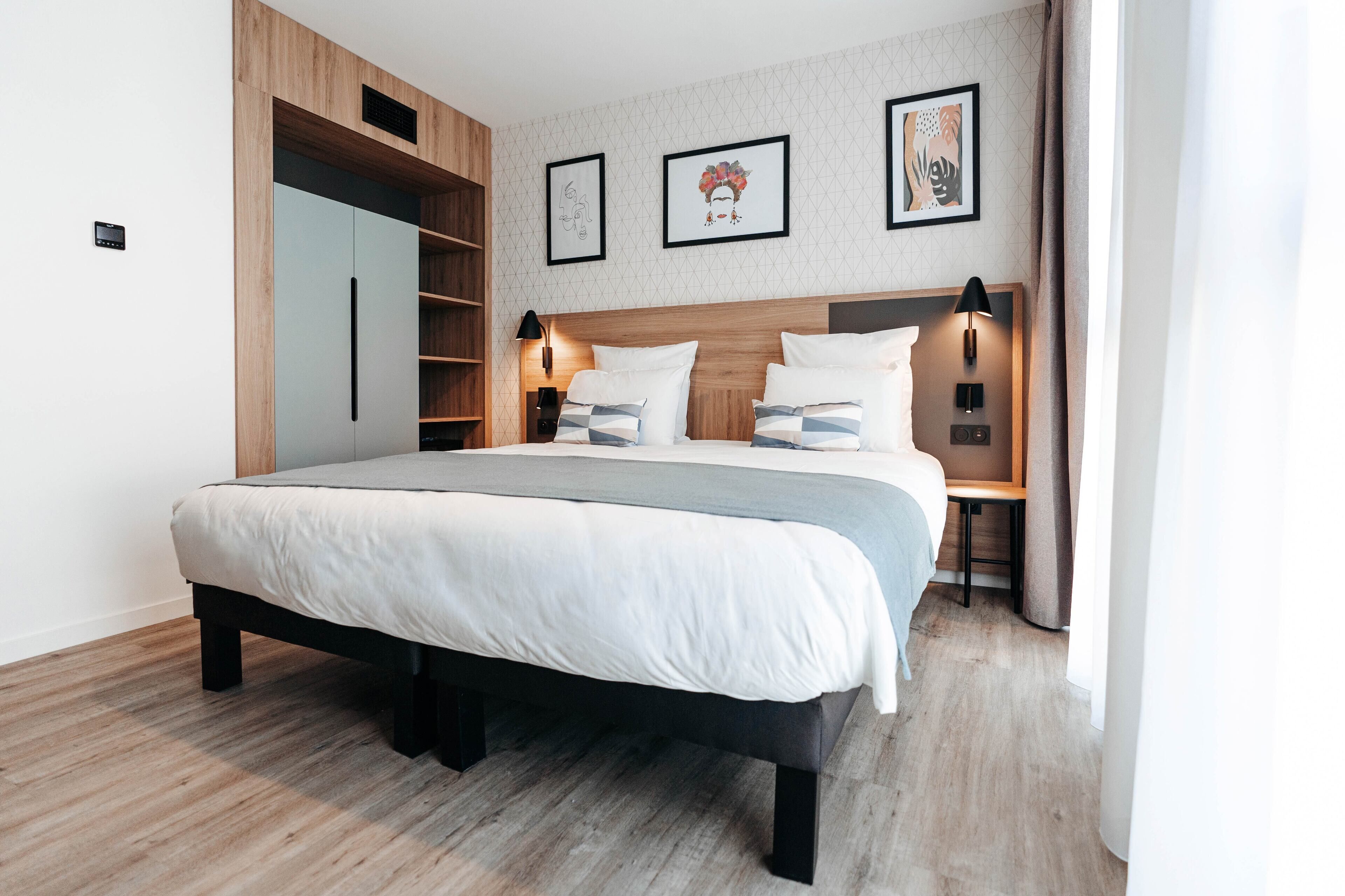 A modern bedroom with a large bed, built-in shelving, and artwork on the walls.