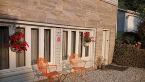 Ein Haus mit Steinverkleidung, zwei Fenster mit Fensterläden und einer Schotterauffahrt.