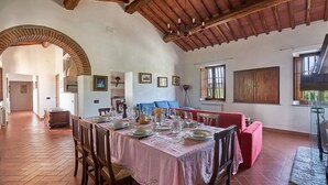 Un coin repas avec une table dressée pour quatre personnes, un canapé rouge et un lustre.