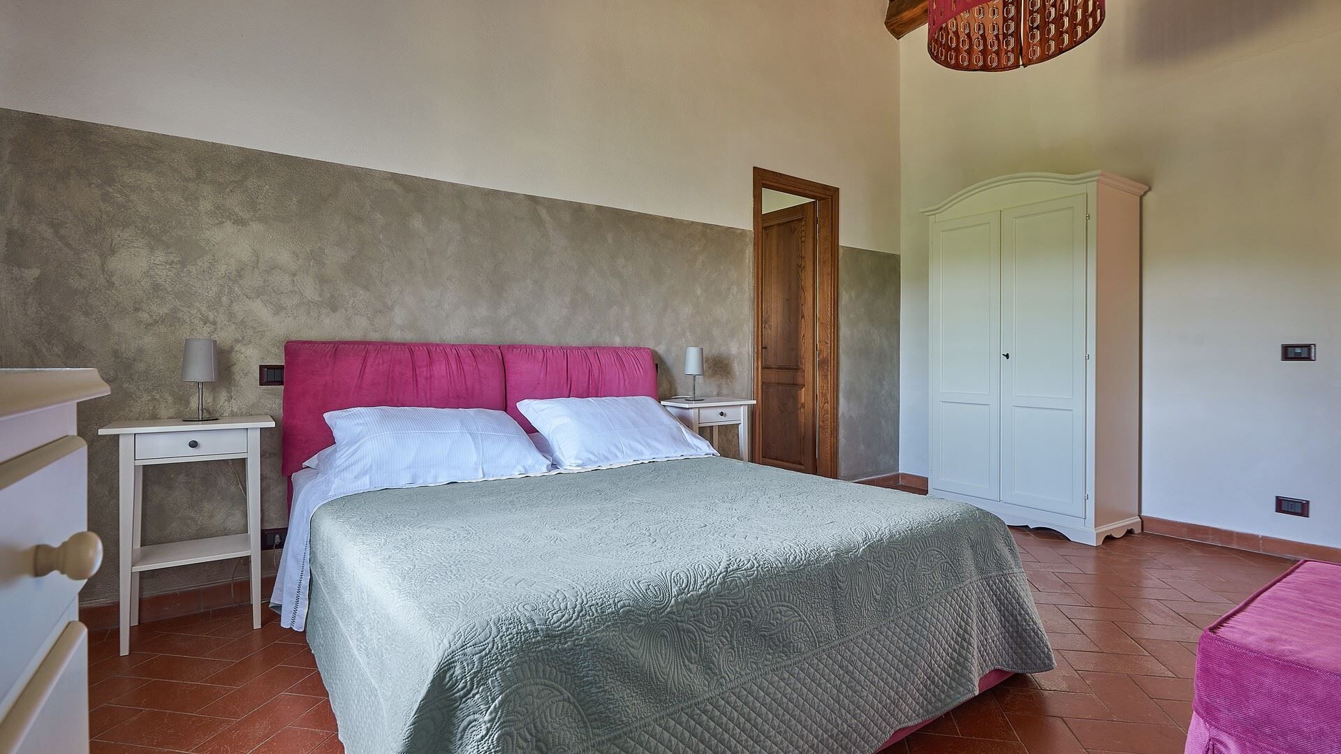 Une chambre à coucher avec un lit, des tables de chevet, une armoire et une porte.