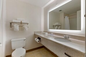 Un baño con inodoro, lavamanos, espejo, toallero y cortina de ducha.