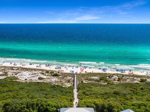 A beach with clear turquoise waters, a sandy shore, and a pier extending into the sea.