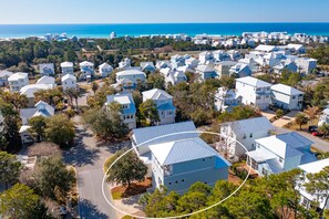 Vista aérea de uma área residencial costeira, com casas, ruas e uma visão clara do oceano.
