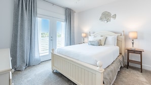 Een slaapkamer met een bed, twee nachtkastjes met lampen, een plafondventilator, een decoratie van een vis en uitzicht door een glazen deur.