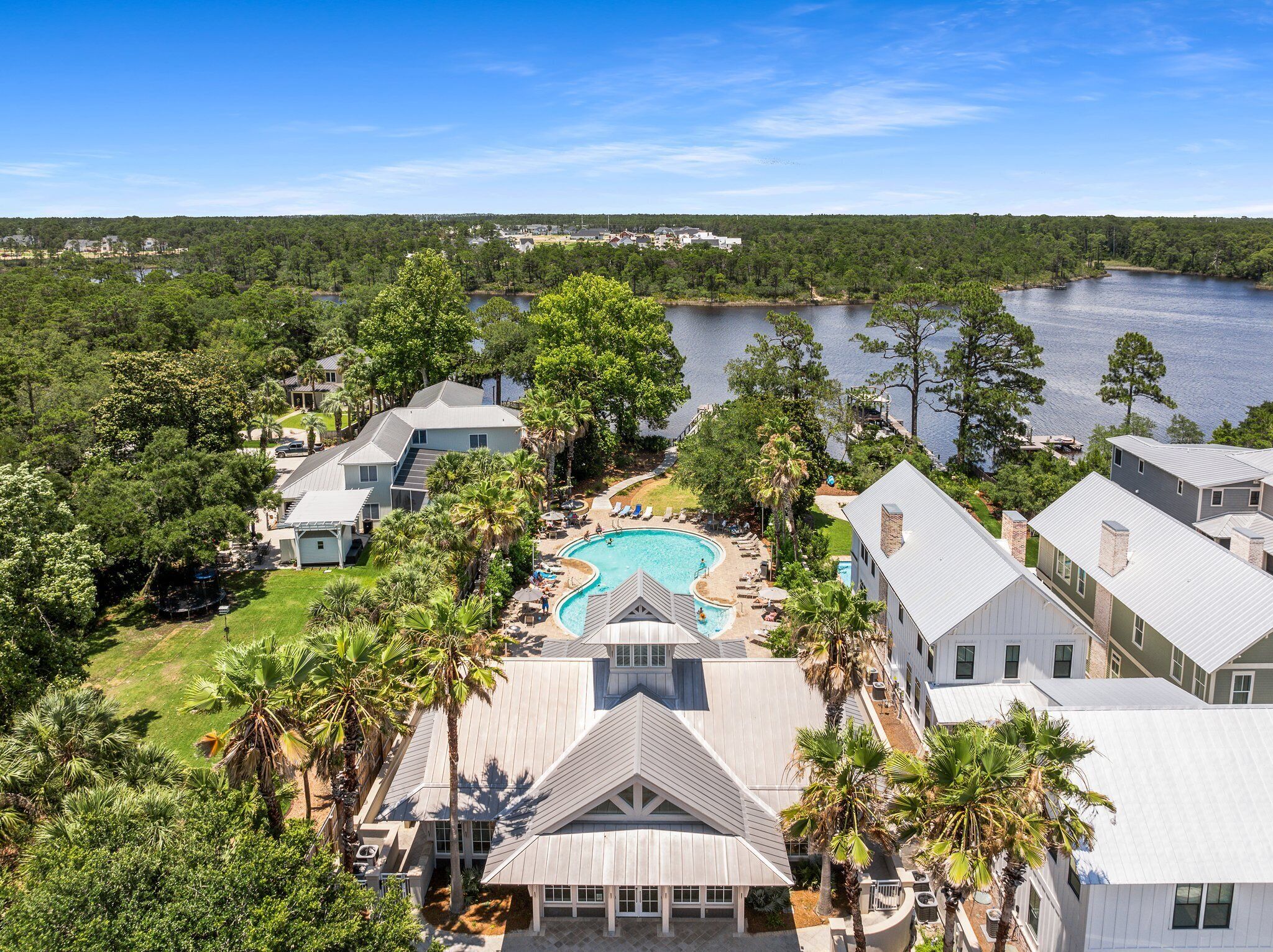 Un quartier résidentiel doté d’une piscine, entouré de maisons, d’arbres et d’un lac.