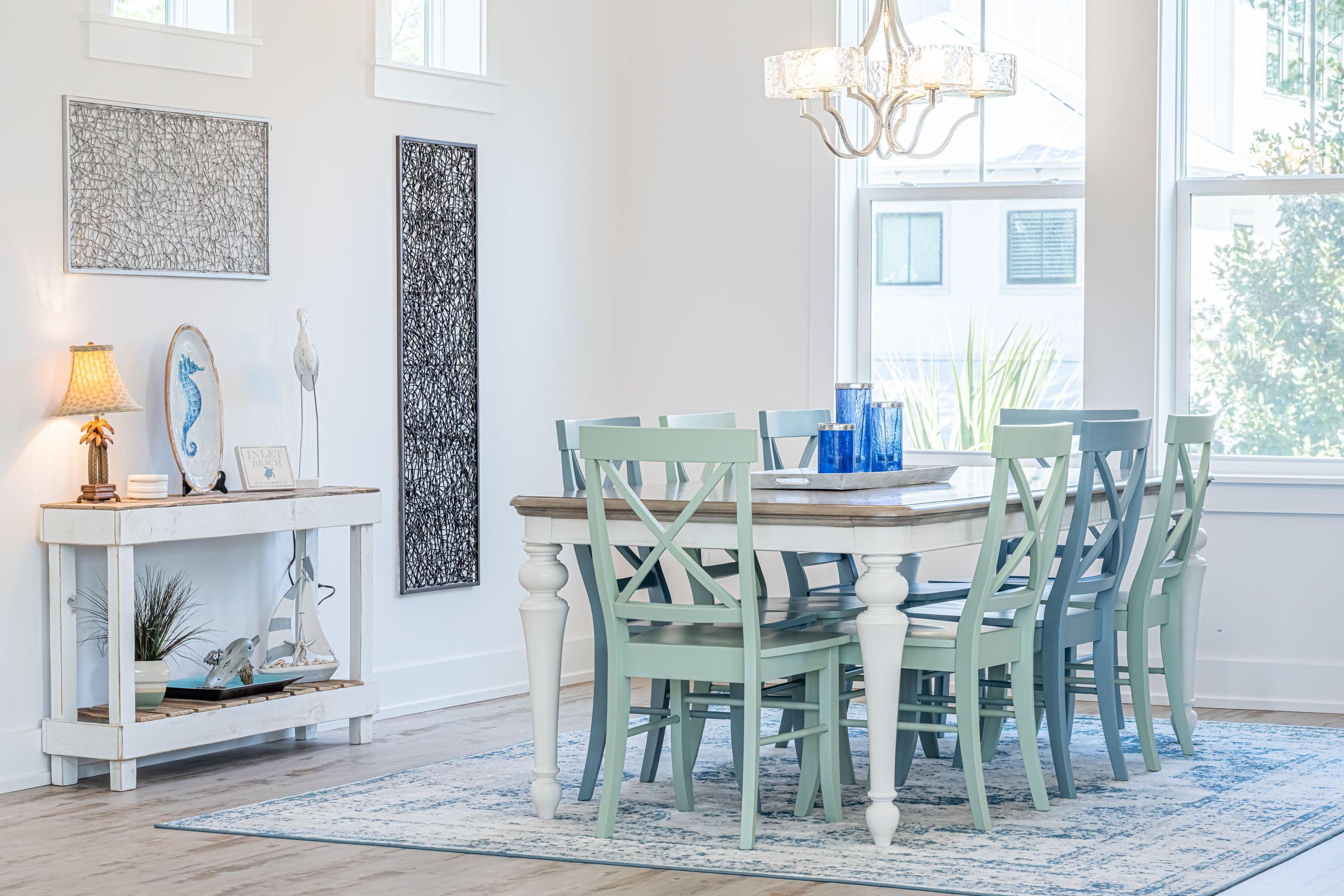 A dining area with a round table, green chairs, and a white console table with decorative items.