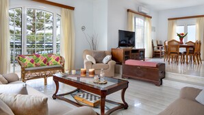 A spacious living room with a large window, a television, a dining area, and a cozy seating arrangement. - Sunset Home with sea view (Chania)