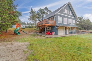 A two-story house with a deck, a play area with a slide, and a grassy yard. - Steps to beach, Ping Pong, XBox, Foosball, WiFi, Private Deck (SandCastle) (Ocean Park)