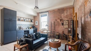 A modern kitchen with dark cabinets, a black sofa, and a rustic brick wall.