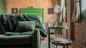 A cozy room with a green sofa, a small side table, and a green chair. - Pickle Factory Hotel—2BR Near Stadiums & Downtown (Covington)