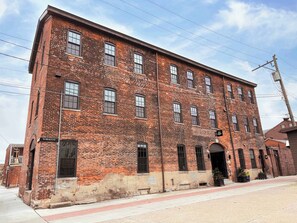 A large, multi-story brick building with a flat roof and multiple windows. - Pickle Factory Hotel—2BR Near Stadiums & Downtown (Covington)