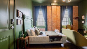 A bedroom with a bed, a chair, a small table, and a window with curtains. - Pickle Factory Hotel—2BR Near Stadiums & Downtown (Covington)