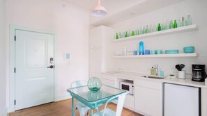 Una cocina moderna con armarios blancos, una mesa de vidrio y una cafetera.