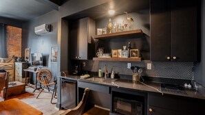 A modern kitchen with dark cabinetry, a black and white tiled backsplash, and a wooden table with chairs.