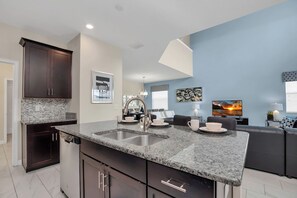 A modern kitchen with granite countertops, dark cabinetry, and a built-in dishwasher.
