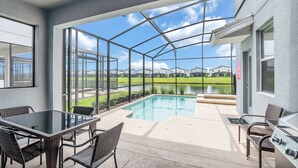 Eine überdachte Terrasse mit Glasveranda, Pool und Gartenmöbeln.