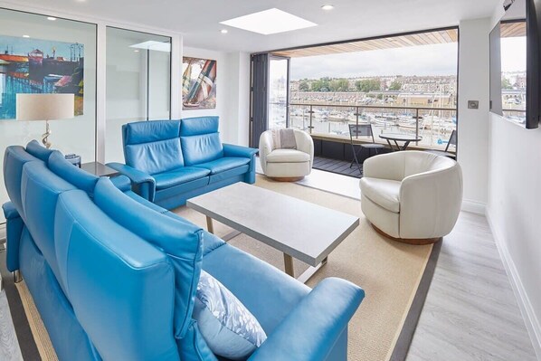 A modern living room with a blue sofa set, a white armchair, and a coffee table. - Host & Stay | The Townhouse (Whitby)