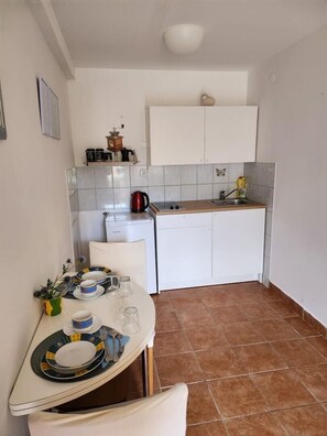 A compact kitchen with white cabinets, a sink, and a dining area with a table set for two.