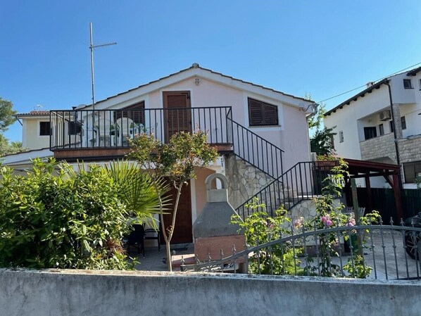 A residential building with a balcony, a chimney, and a small garden area.