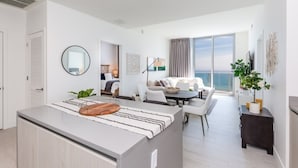 A modern kitchen with a central island, a dining area with a table and chairs, and a living space with a sofa and a large window overlooking the ocean. - Hyde Beach House Luxury Condo-resort 2 Bedroom Condo by RedAwning (Hollywood)