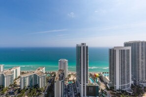 A high-rise hotel with a view of the ocean, featuring multiple balconies and a pool area.