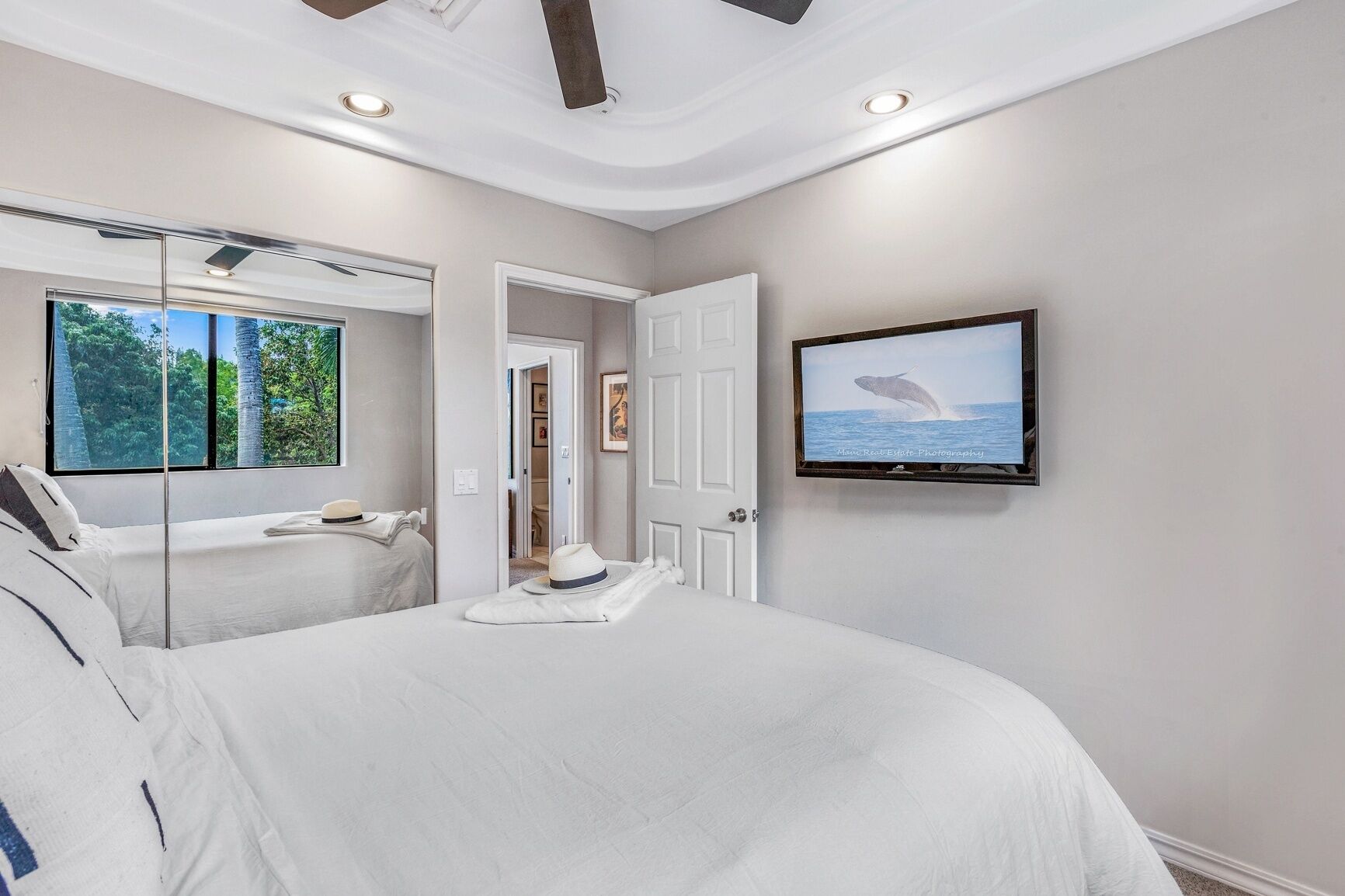A modern bedroom with a large bed, a television, and a view of the outdoors.
