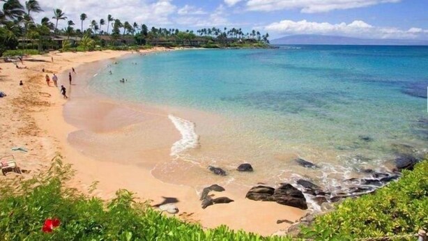 A beach with clear turquoise water, a sandy shore, and palm trees in the background. - Napili Gardens B7 3 Bedroom 3 Townhouse by RedAwning (Lahaina)
