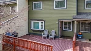 A green house with a deck, two white chairs, and a small window. - Whistler Village - Redwood 10 2 Bedroom Condo by RedAwning (Steamboat Springs)