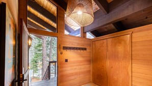 A wooden interior with a large sliding door leading to a deck, a hanging light fixture, and a wall-mounted coat rack. - Beautiful 3-Bedroom Contemporary Mountain Home in Northstar by RedAwning Save 10% on 3 Nights, 15% on 5 Nights! (Truckee)